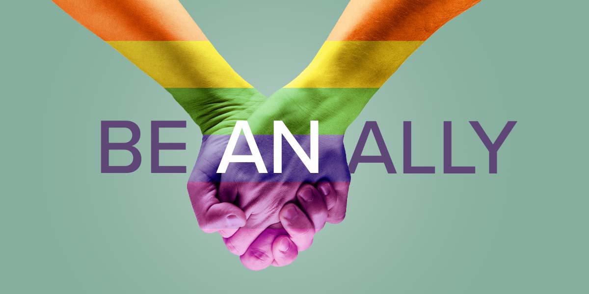 Two people holding hands painted with LGBTQ+ colors.
